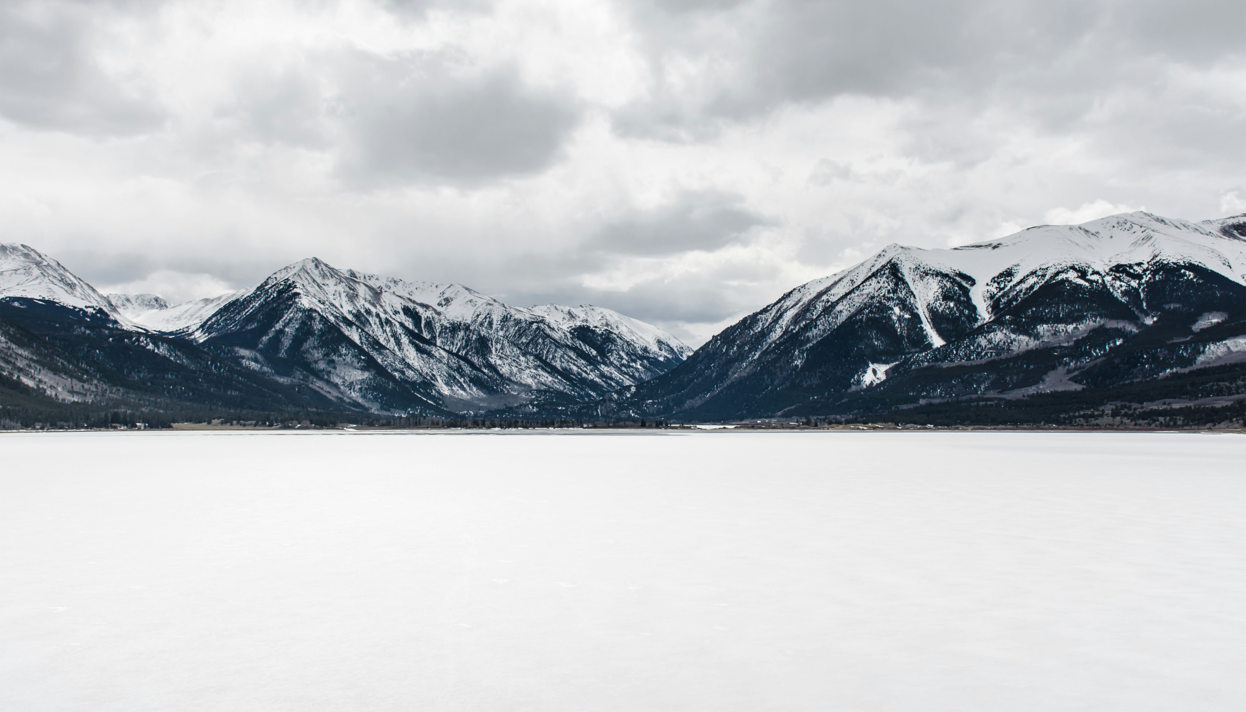 Frozen Snow-Covered Body of Water Near Mountain Peak During Daytime An Frozen Snow-Covered Body of Water Near Mountain Peak During Daytime